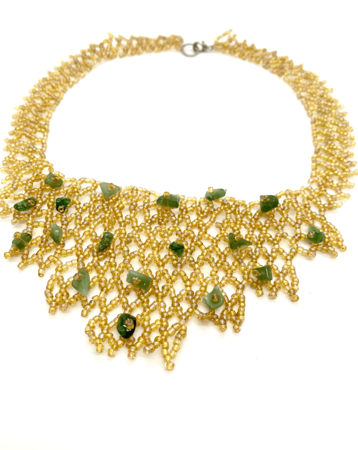 Gold beaded necklace with green accents. The necklace has a cascading design and features a mix of small, round beads and larger, irregularly shaped beads.