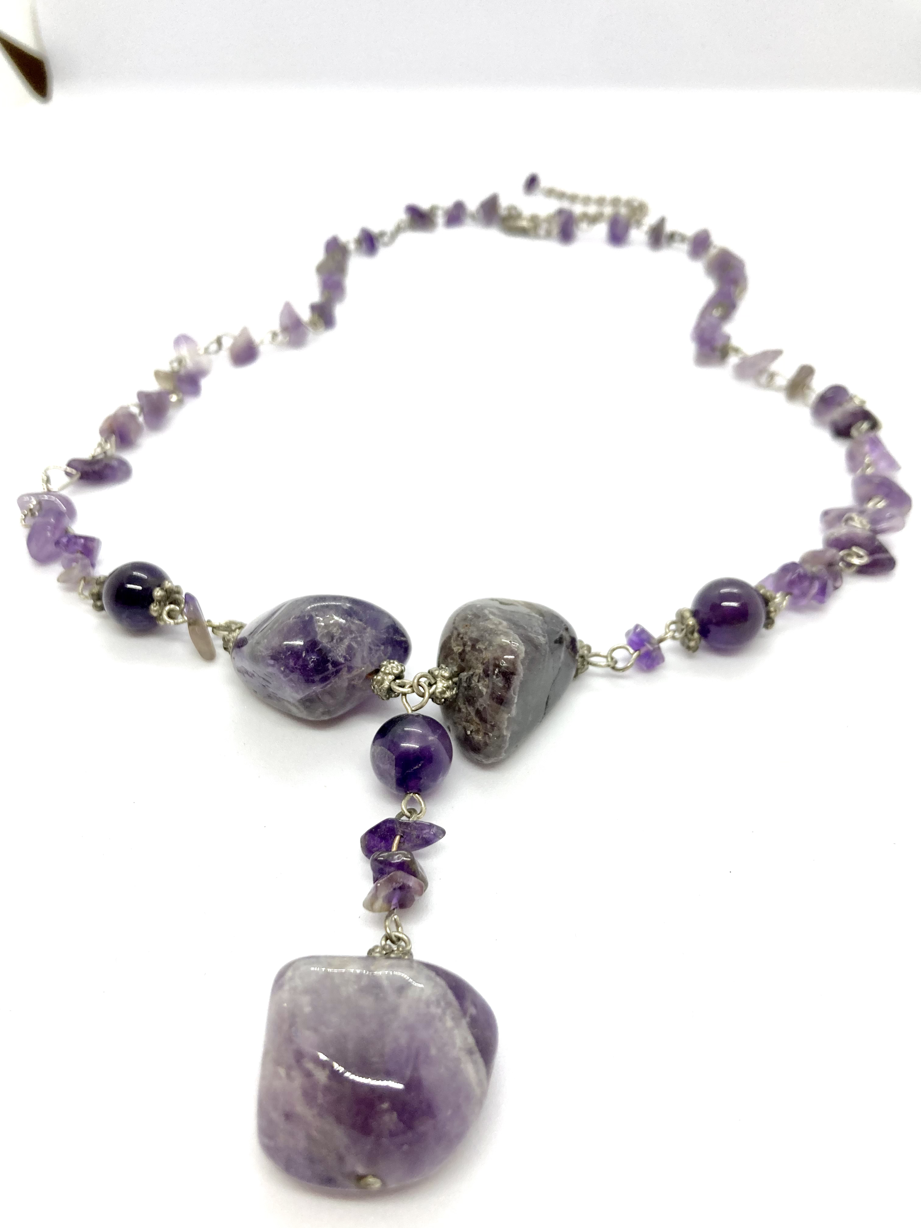  A multi-strand beaded necklace featuring amethyst stones in various sizes and shapes, with a larger amethyst pendant at the center.