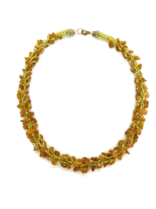 A multi-strand beaded necklace featuring golden amber beads and green accent beads.