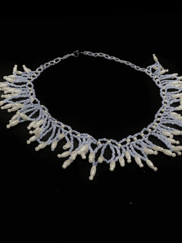 A delicate beaded necklace with a fringe of white and light blue beads. The necklace has a silver clasp.