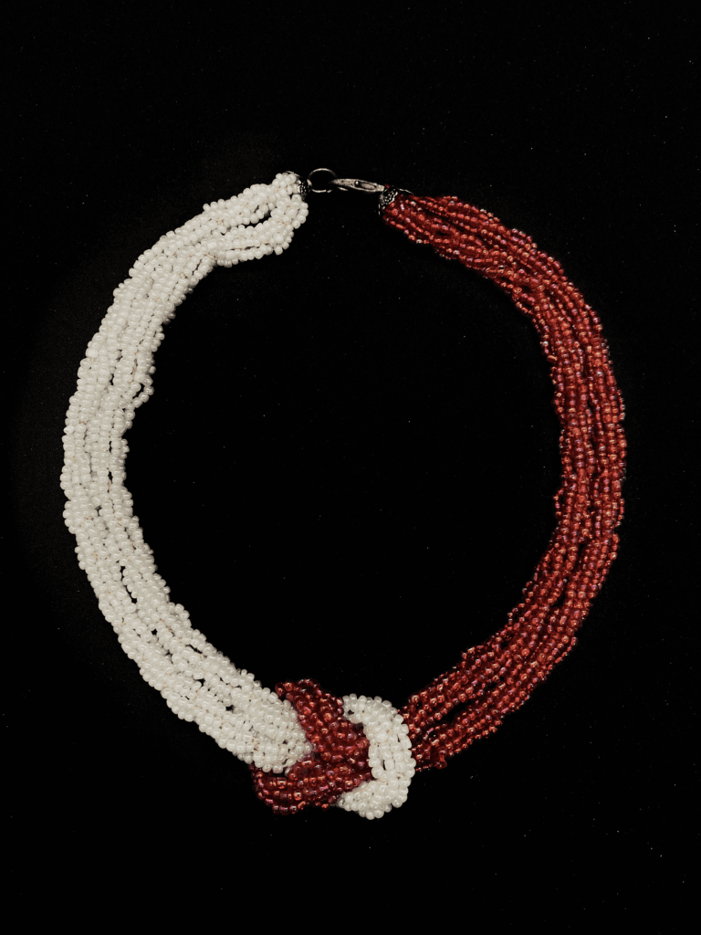 A handcrafted beaded necklace with a unique knotted design and a contrasting color scheme.