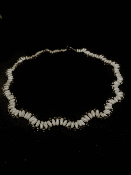 A delicate beaded necklace featuring white pearls arranged in a flowing design.