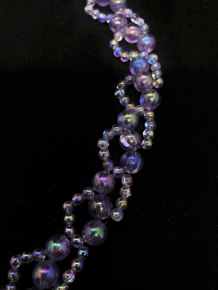 A multi-strand beaded necklace featuring amethyst and iridescent beads, arranged in a spiral pattern.