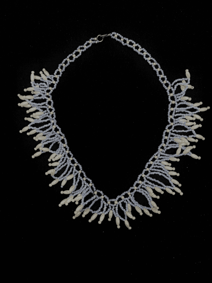 A delicate beaded necklace with a fringe of white and light blue beads. The necklace has a silver clasp.